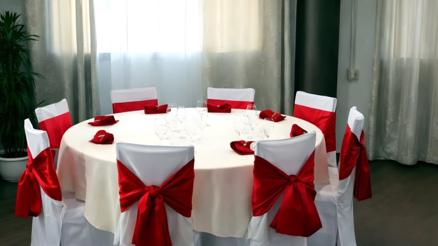 Mesa de banquete con sillas decoradas con lazos rojos tipo moño