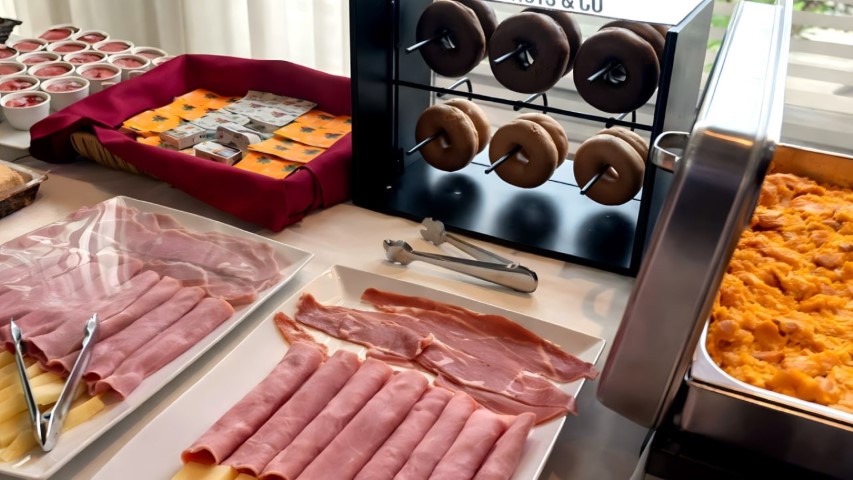 Vista panorámica completa del desayuno buffet para grupos y eventos con zona caliente, pan y fiambres