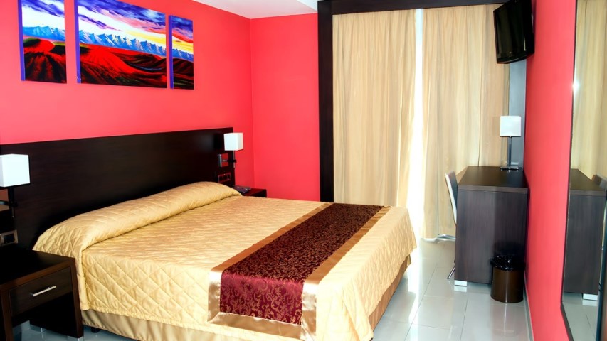 Habitación doble con colcha dorada y tríptico de arte