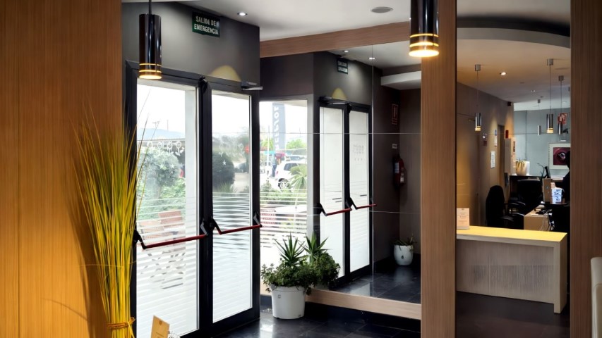 Entrada principal del hotel con puertas de cristal y recepción visible