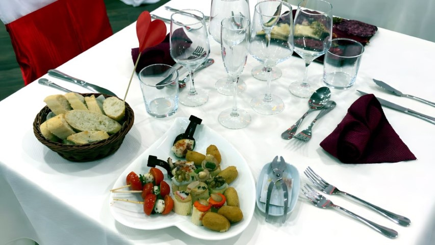 Mesa de restaurante con aperitivos, pan y vajilla completa en Hotel Ruta Romana