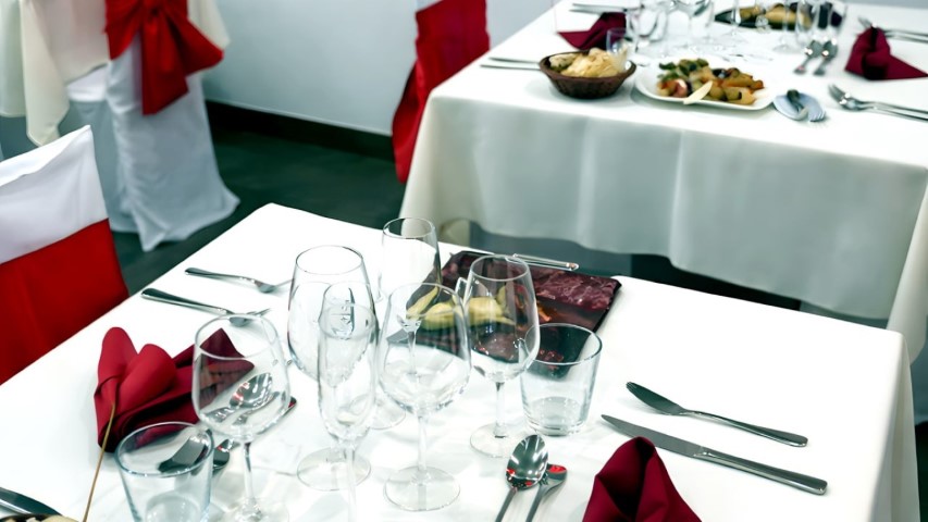 Múltiples mesas del restaurante preparadas con manteles blancos y copas