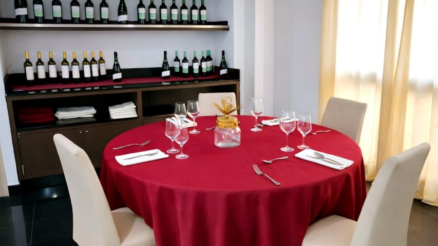 Mesa redonda elegantemente decorada con mantel rojo completo