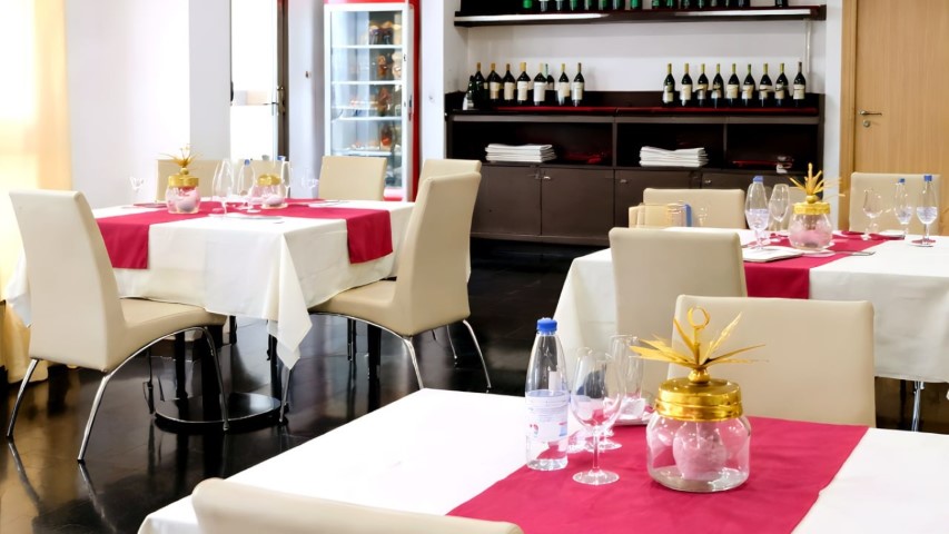 Sala del restaurante mostrando la estantería de vinos y mesas preparadas